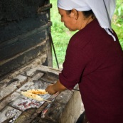 Femme bolivienne en train de préparer de la cuisine traditionnelle (des sonsos : manioc appele egalement yuca, et fromage frais) au feu de bois, dans une petite maisonnette dans la jungle, foret en arriere plan. Bolivie.