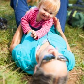 Bebe petite fille enfant avec sa grand-mere allongee dans l'herbe en train de jouer.