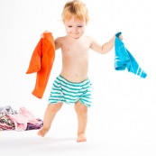 Bebe petite fille . Portrait. En train de s'amuser avec des vetements et un chariot. Habits. Enfant.