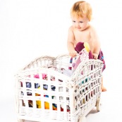 Bebe petite fille . Portrait. En train de s'amuser avec des vetements et un chariot. Habits. Enfant.