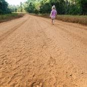 Village de Saul en Guyane. Pas sur le sol en latérite. Route. Petite fille, bebe, en train de marcher.