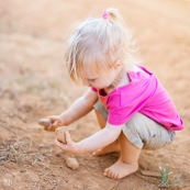 Petite fille en train de jouer avec de la terre et des cailloux. Bebe.