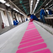 Usine chinoise de fabrication de chaussures et autres produits (protections, sacs...). Ouvriers a la chaine, en train de realiser des serigraphies. Chine, Shenzhen, usine du monde. Travail plus de 70 heures par semaine, a faible couts, pour utilisation des produits par les pays "riches". Coloration de tissus en rose.