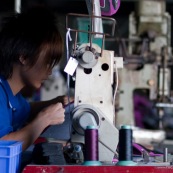 Usine en Chine. Ouvrier en train de faire de la couture sur machine a coudre.