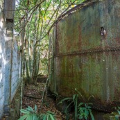 Ancienne rhumerie a Matoury, Guyane francaise.  La vegetation reprend ses doits.  Cuve rouillee par le temps, percee.