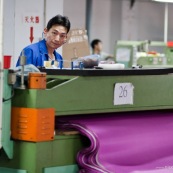 Usne en Chine. Ouvrier en train de decouper des tissus.